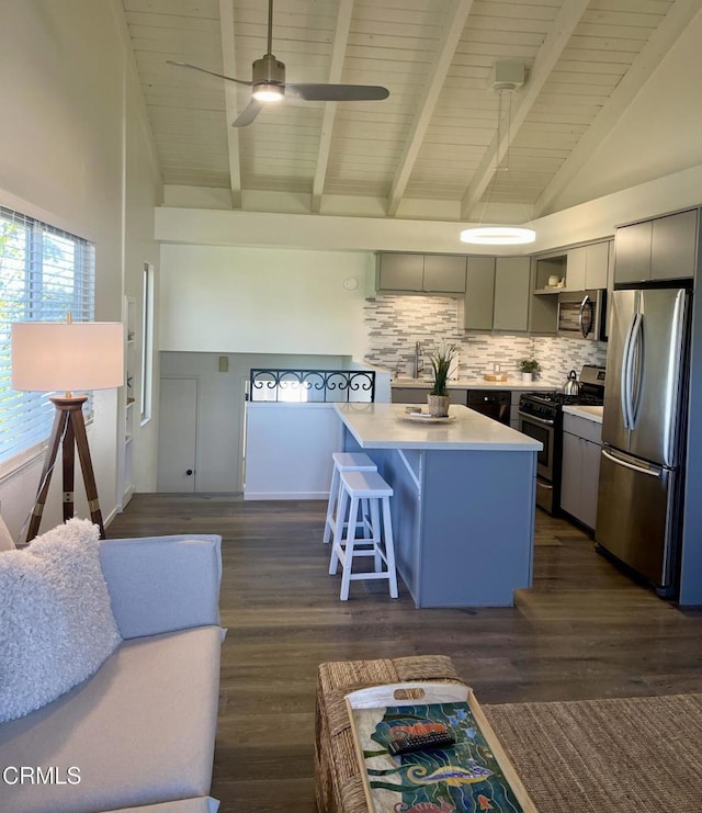 kitchen with stainless steel appliances, a breakfast bar, light countertops, a center island, and tasteful backsplash