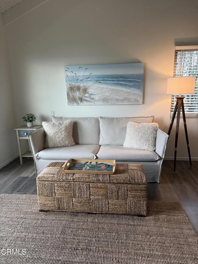 living room featuring vaulted ceiling, baseboards, and wood finished floors