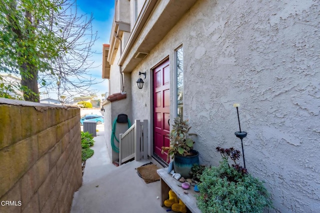 entrance to property featuring central AC, fence, and stucco siding