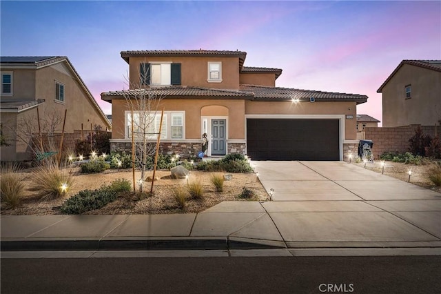 mediterranean / spanish house featuring a garage, a tile roof, stone siding, concrete driveway, and stucco siding