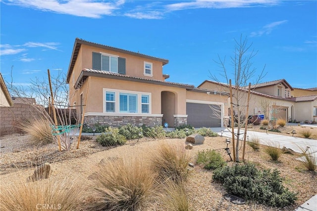 mediterranean / spanish house with an attached garage, stone siding, a tiled roof, driveway, and stucco siding