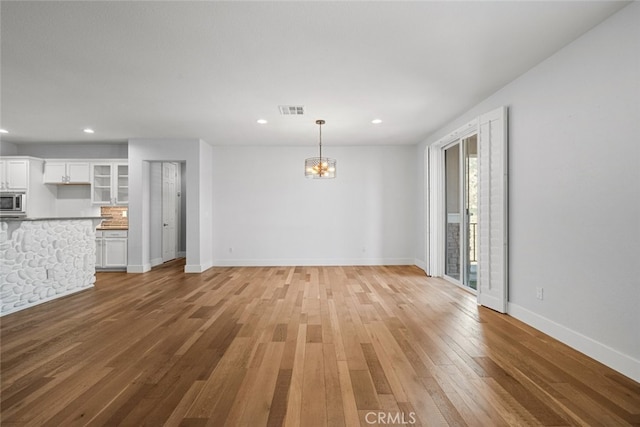 unfurnished living room featuring wood-type flooring and a notable chandelier