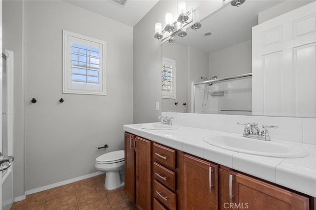 bathroom featuring toilet, an inviting chandelier, vanity, a shower with door, and tile patterned flooring