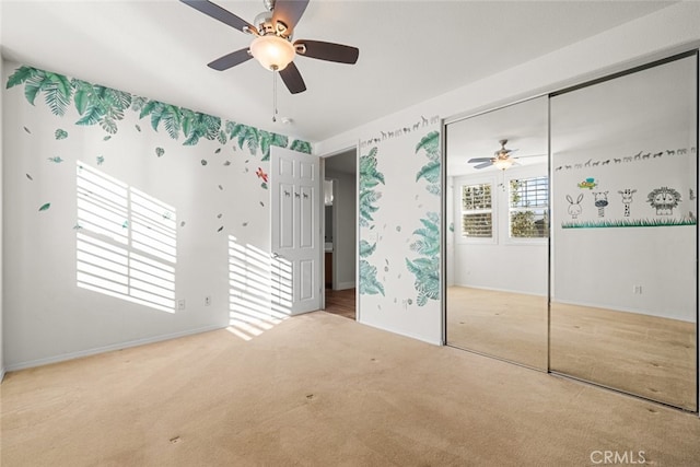 unfurnished bedroom featuring light colored carpet, ceiling fan, and a closet