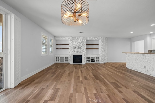 unfurnished living room featuring hardwood / wood-style flooring, a fireplace, and a chandelier