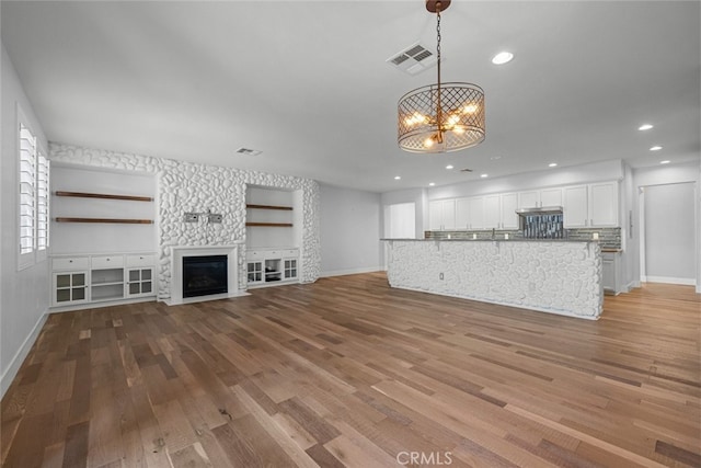 unfurnished living room featuring a chandelier and light wood-type flooring