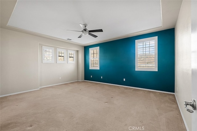 spare room with a wealth of natural light, light colored carpet, and ceiling fan