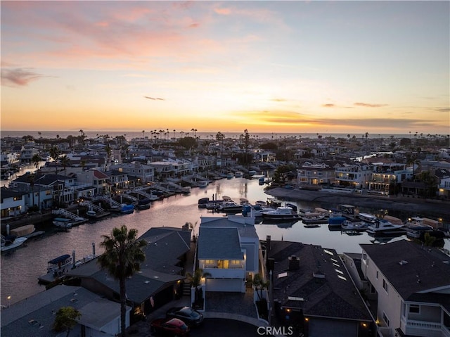 aerial view at dusk featuring a water view