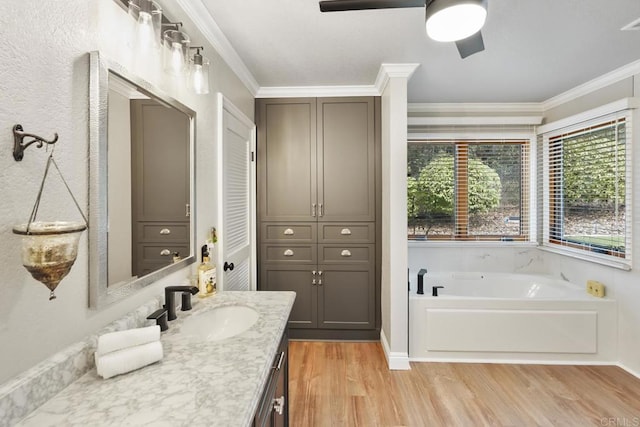 bathroom with ornamental molding, a bath, vanity, hardwood / wood-style flooring, and ceiling fan