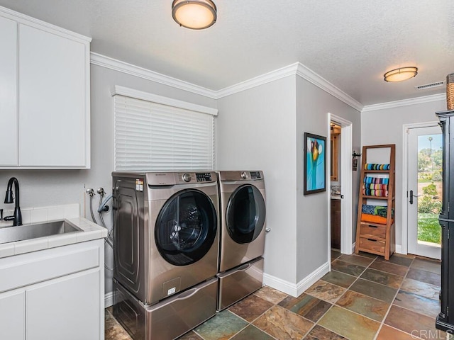 washroom with sink, cabinets, a textured ceiling, ornamental molding, and independent washer and dryer