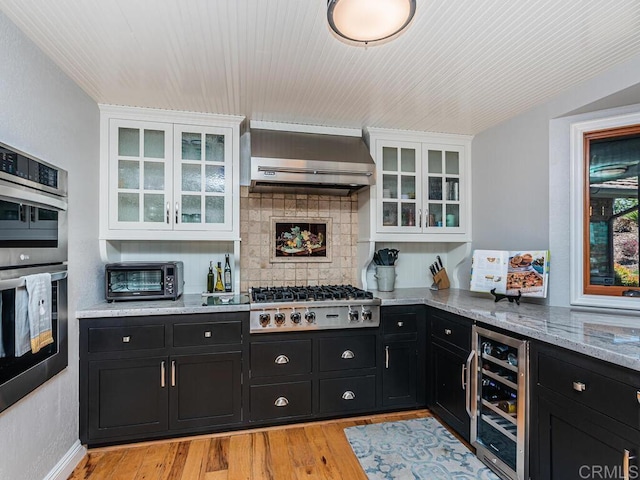 kitchen with light hardwood / wood-style flooring, white cabinetry, stainless steel appliances, beverage cooler, and wall chimney exhaust hood