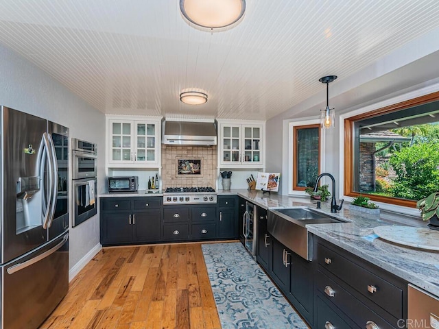 kitchen featuring stainless steel appliances, white cabinetry, sink, and wall chimney range hood