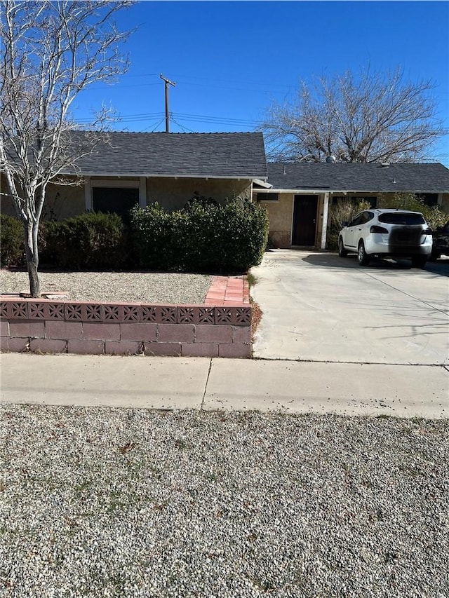 view of front facade featuring a shingled roof and driveway