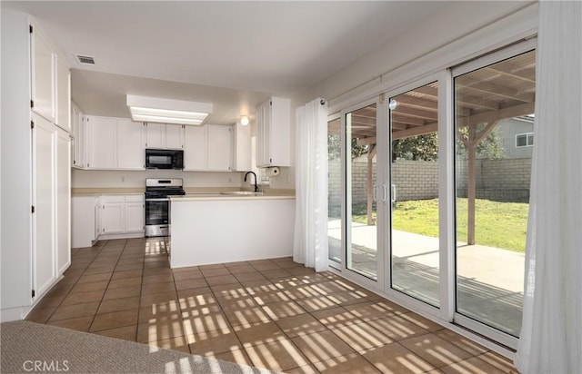 kitchen featuring dark tile patterned floors, white cabinetry, sink, and stainless steel range oven