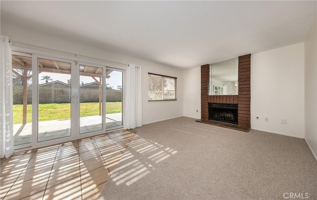 unfurnished living room with a brick fireplace, plenty of natural light, and light carpet