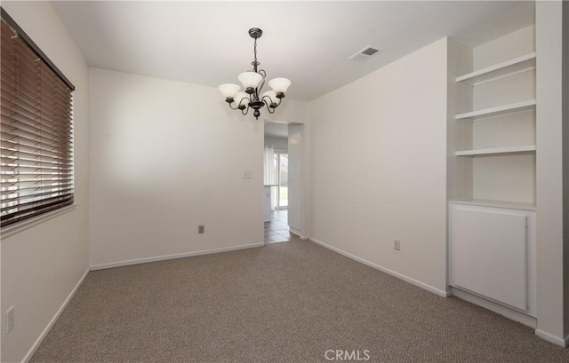 unfurnished room featuring a chandelier and light carpet