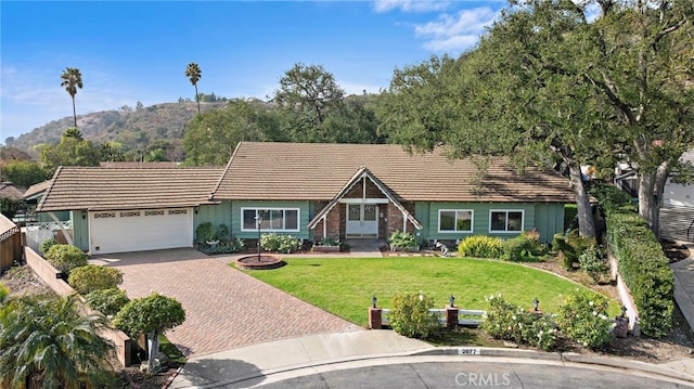 ranch-style house featuring a garage, a mountain view, and a front lawn