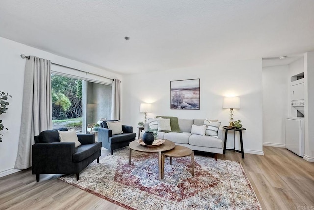 living room featuring light hardwood / wood-style flooring and stacked washer / dryer