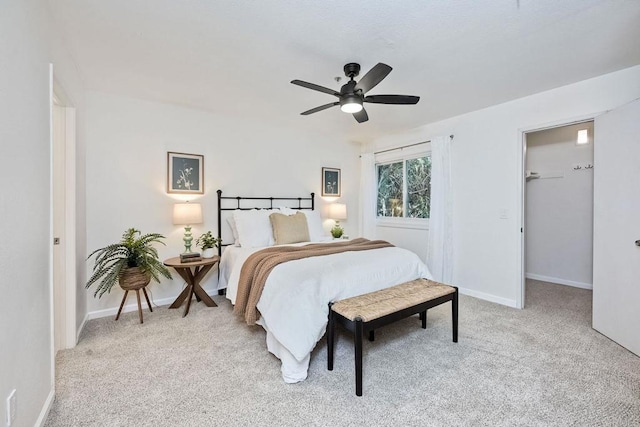 bedroom featuring a walk in closet, light colored carpet, and ceiling fan