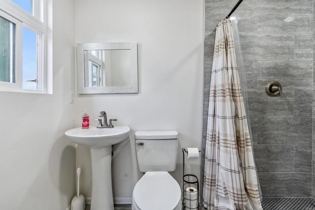 bathroom with toilet, plenty of natural light, sink, and a shower with shower curtain