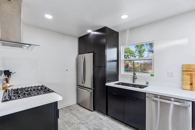 kitchen with wall chimney exhaust hood, appliances with stainless steel finishes, sink, and light wood-type flooring