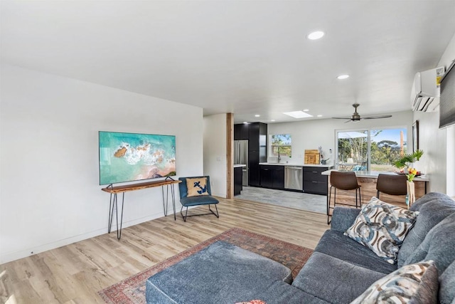 living room with a skylight, light hardwood / wood-style floors, an AC wall unit, and ceiling fan