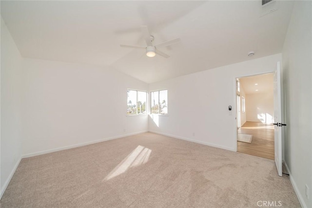 spare room with ceiling fan, lofted ceiling, and light carpet