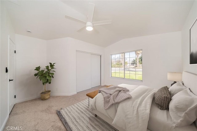 bedroom with light carpet, vaulted ceiling, a closet, and ceiling fan