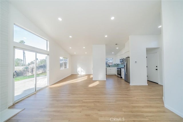 unfurnished living room with high vaulted ceiling and light wood-type flooring