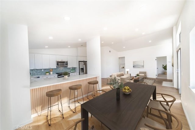 dining area with lofted ceiling and light wood-type flooring