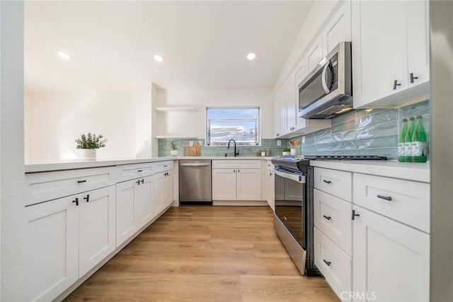 kitchen with sink, light hardwood / wood-style flooring, white cabinets, stainless steel appliances, and backsplash