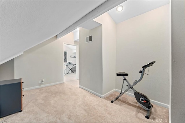 exercise room featuring vaulted ceiling and light colored carpet