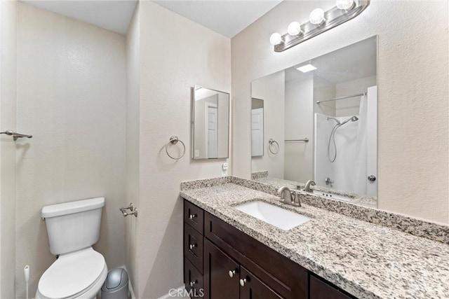 bathroom with vanity, toilet, and a shower