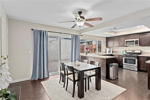 dining area with ceiling fan, dark hardwood / wood-style flooring, and a raised ceiling