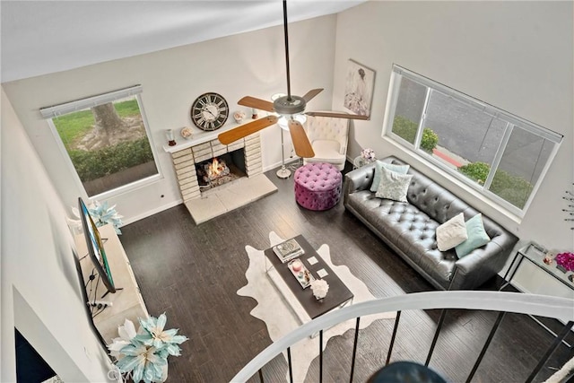 living room featuring hardwood / wood-style flooring, ceiling fan, a fireplace, and vaulted ceiling