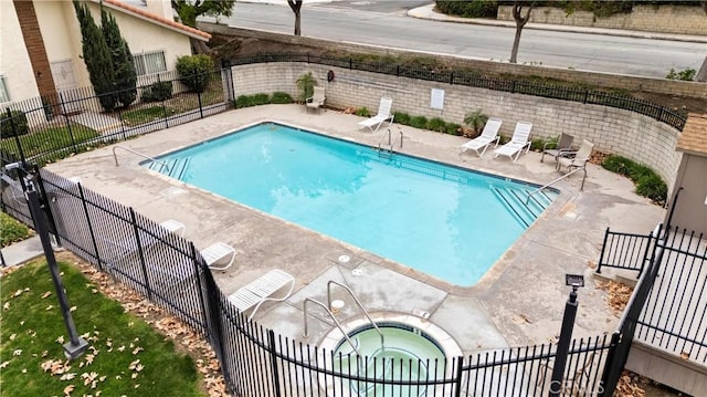 view of swimming pool featuring a hot tub and a patio