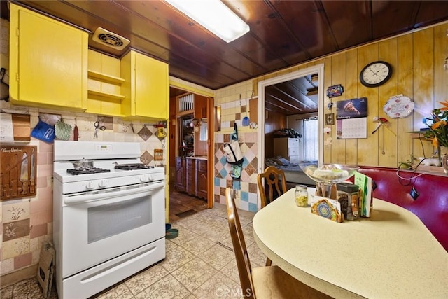 kitchen with wood ceiling, wooden walls, and white range with gas stovetop