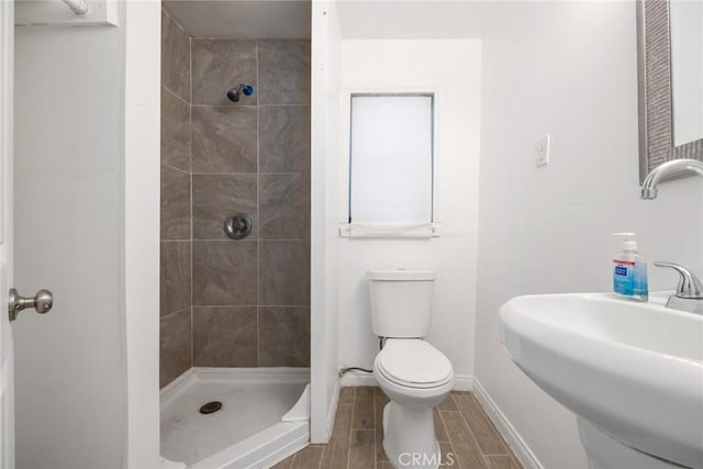 bathroom featuring toilet, sink, and a tile shower