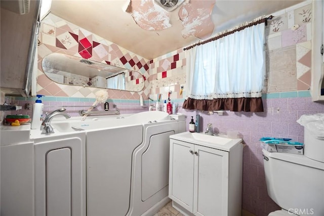 bathroom with vanity, toilet, and tile walls