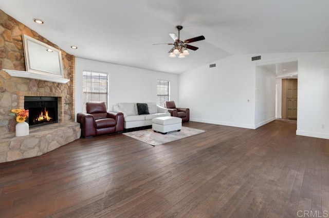 living room with lofted ceiling, a stone fireplace, dark hardwood / wood-style flooring, and ceiling fan