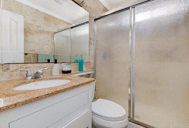 bathroom with vanity, crown molding, a shower with shower door, and toilet