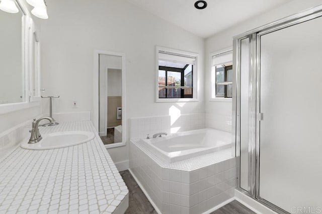 bathroom featuring vanity, wood-type flooring, and plus walk in shower