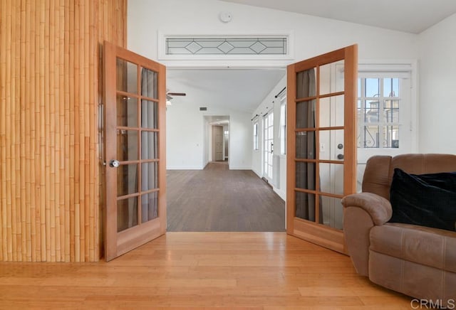 corridor featuring lofted ceiling, french doors, and light wood-type flooring