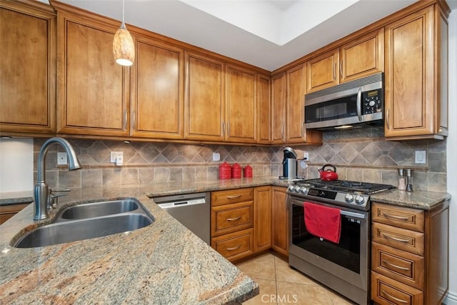 kitchen featuring light tile patterned flooring, sink, light stone counters, hanging light fixtures, and stainless steel appliances