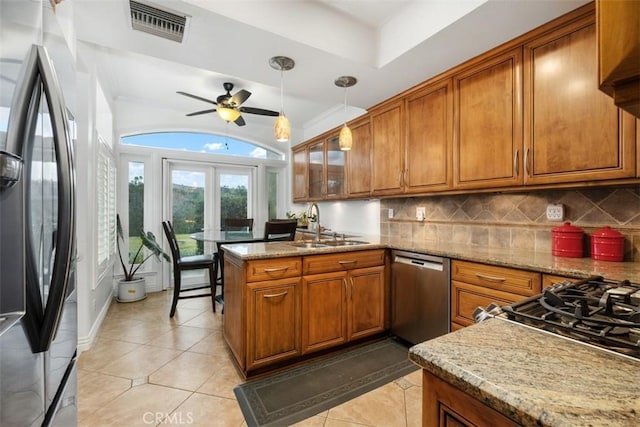 kitchen featuring decorative light fixtures, tasteful backsplash, sink, stainless steel appliances, and light stone countertops