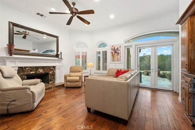 living area featuring hardwood / wood-style flooring, ornamental molding, a high end fireplace, and french doors