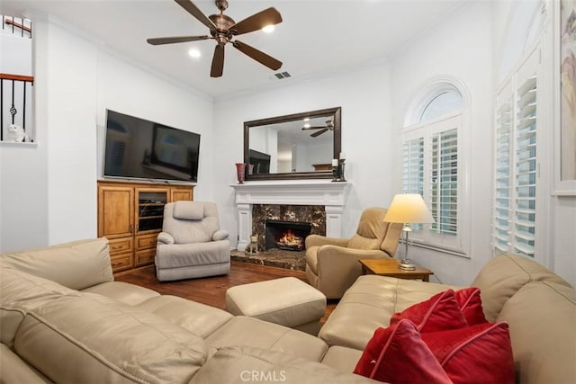 living room featuring crown molding, hardwood / wood-style floors, ceiling fan, and a high end fireplace