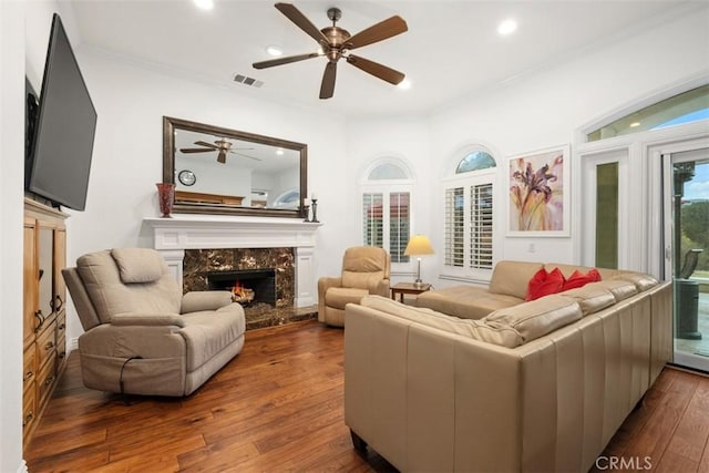 interior space featuring a fireplace, ornamental molding, dark hardwood / wood-style floors, and ceiling fan