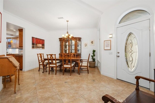 dining area with crown molding, a chandelier, and light tile patterned floors