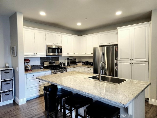 kitchen featuring stainless steel appliances, an island with sink, and white cabinets